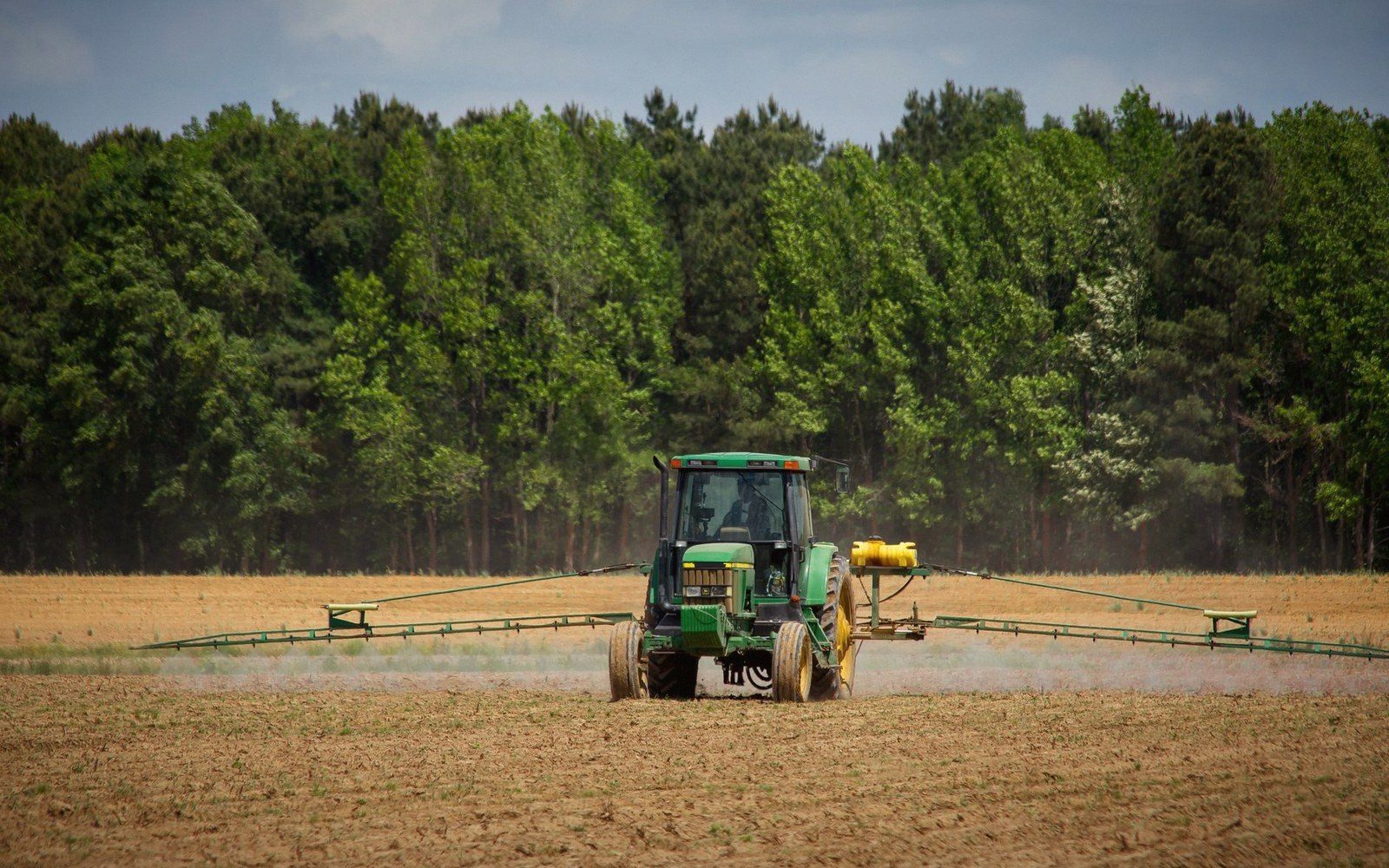 A tractor with a spray boom working a field